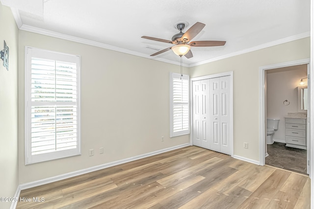 unfurnished bedroom featuring ceiling fan, wood-type flooring, ensuite bathroom, and crown molding