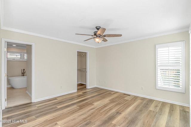 unfurnished bedroom with ceiling fan, light hardwood / wood-style flooring, connected bathroom, ornamental molding, and a walk in closet