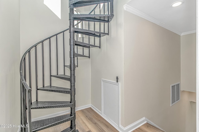 staircase featuring wood-type flooring and crown molding