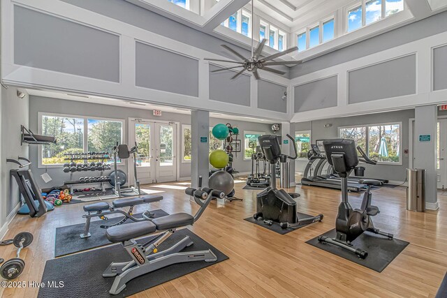 workout area with ceiling fan, french doors, hardwood / wood-style floors, and a towering ceiling