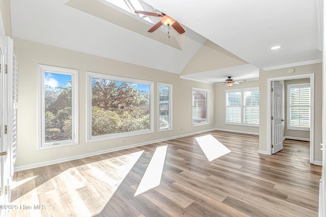 unfurnished living room featuring ceiling fan, vaulted ceiling with skylight, crown molding, and light wood-type flooring