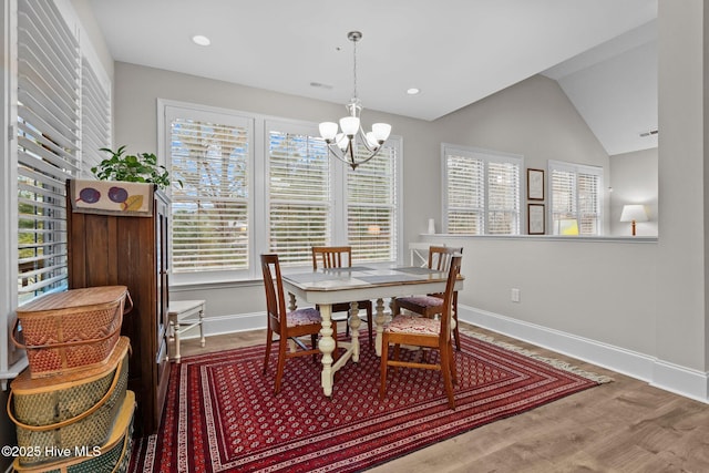 dining space featuring an inviting chandelier, hardwood / wood-style flooring, and vaulted ceiling