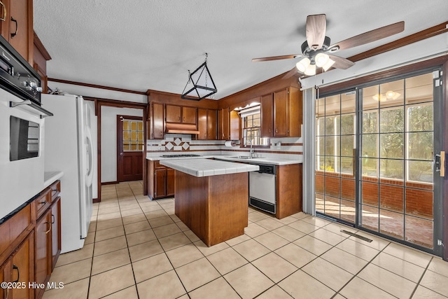 kitchen with tile countertops, a kitchen island, appliances with stainless steel finishes, ornamental molding, and light tile patterned floors