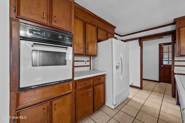 kitchen with light tile patterned floors, tile counters, tasteful backsplash, white appliances, and ornamental molding