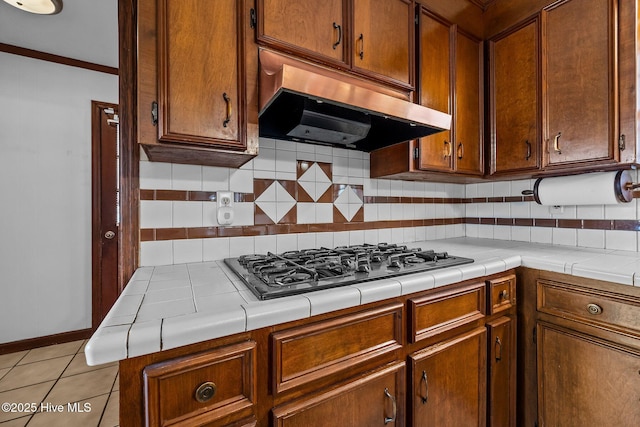 kitchen with extractor fan, tile countertops, decorative backsplash, stainless steel gas cooktop, and light tile patterned floors