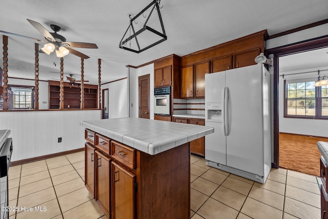 kitchen with tile countertops, white appliances, a textured ceiling, a kitchen island, and crown molding