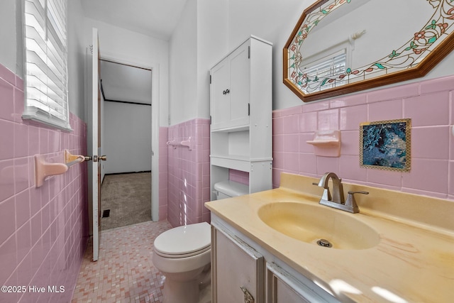 bathroom featuring toilet, vanity, tile walls, and tile patterned floors