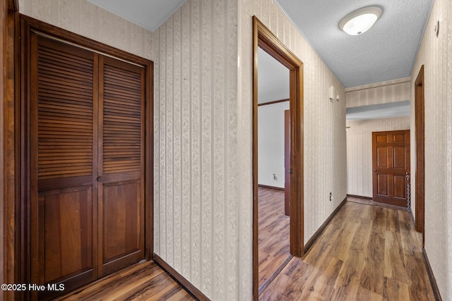 hallway with a textured ceiling and hardwood / wood-style floors