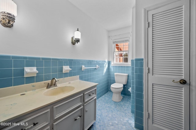 bathroom featuring toilet, tile patterned flooring, tile walls, and vanity