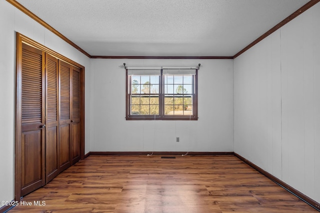 unfurnished bedroom with a textured ceiling, a closet, dark hardwood / wood-style flooring, and ornamental molding