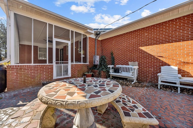 view of patio with ceiling fan and a sunroom