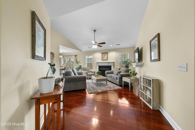 living room featuring lofted ceiling, a tile fireplace, dark hardwood / wood-style floors, and ceiling fan