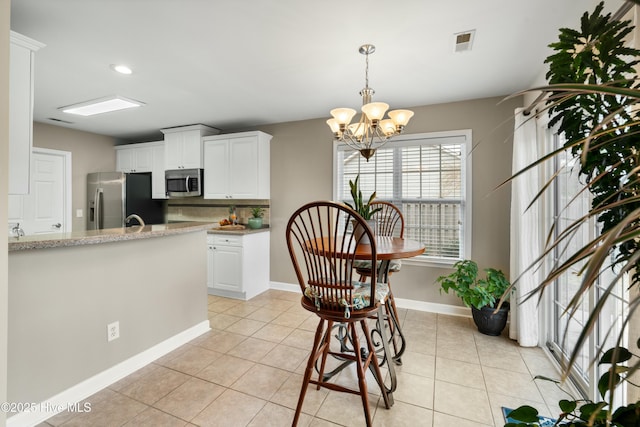 kitchen with light stone countertops, white cabinetry, appliances with stainless steel finishes, and light tile patterned flooring