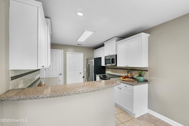 kitchen featuring light tile patterned floors, appliances with stainless steel finishes, kitchen peninsula, light stone countertops, and white cabinets