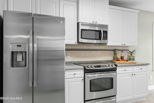 kitchen with appliances with stainless steel finishes, white cabinetry, backsplash, light tile patterned floors, and light stone counters