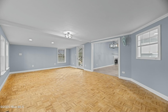 spare room featuring an inviting chandelier, ornamental molding, and light parquet flooring