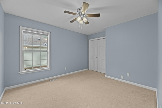 unfurnished bedroom featuring light colored carpet, ceiling fan, and a closet