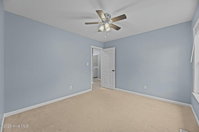 unfurnished bedroom featuring light carpet, washer / dryer, and ceiling fan