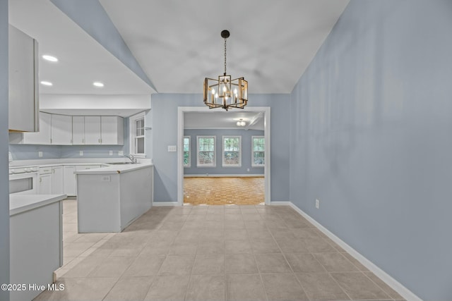 kitchen featuring pendant lighting, sink, white cabinets, vaulted ceiling, and oven