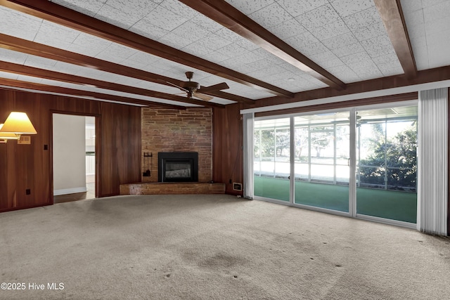 unfurnished living room with a fireplace, beamed ceiling, ceiling fan, and wooden walls