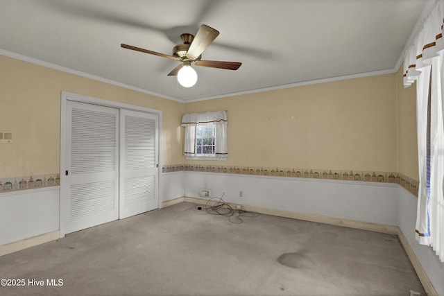 unfurnished bedroom with ceiling fan, crown molding, a closet, and light carpet