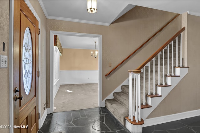 carpeted foyer with an inviting chandelier and ornamental molding