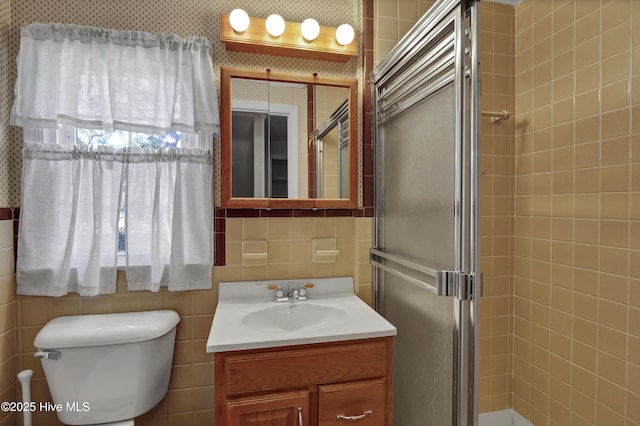 bathroom with toilet, vanity, and a shower with door