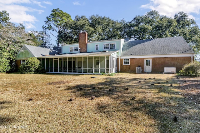 rear view of house with central AC unit, a sunroom, and a yard