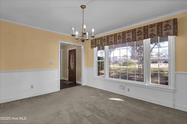 unfurnished dining area with dark colored carpet, ornamental molding, and an inviting chandelier