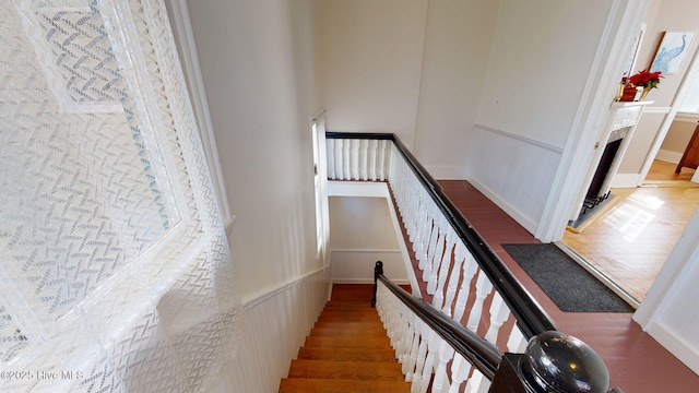 stairs with wood finished floors and a fireplace