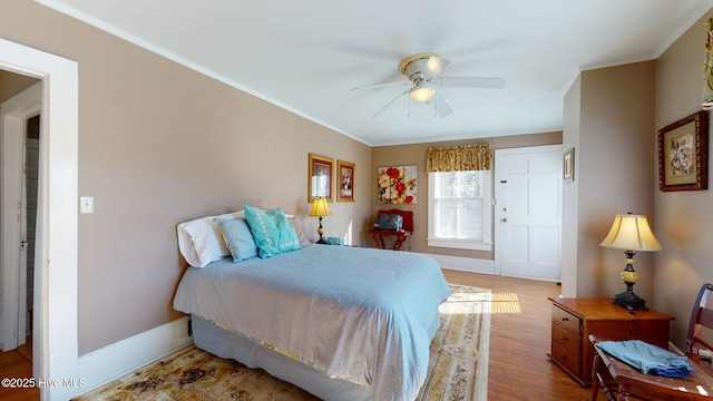 bedroom featuring baseboards, a ceiling fan, wood finished floors, and ornamental molding