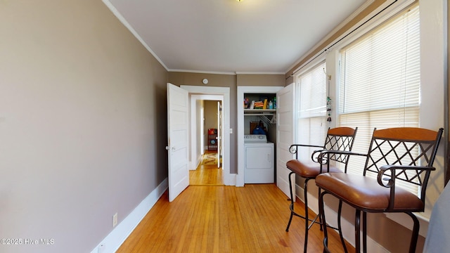 living area with washer / dryer, light wood-style floors, baseboards, and ornamental molding
