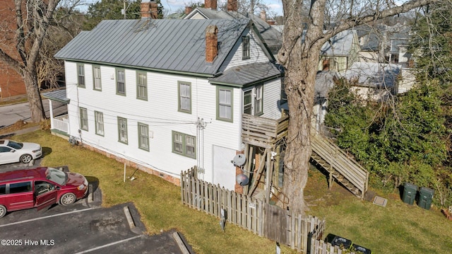 exterior space with uncovered parking, fence, a chimney, and a lawn