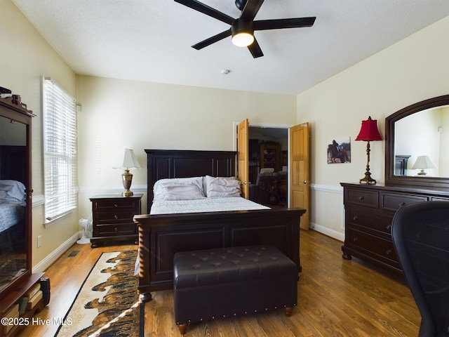 bedroom featuring ceiling fan, multiple windows, and dark hardwood / wood-style floors