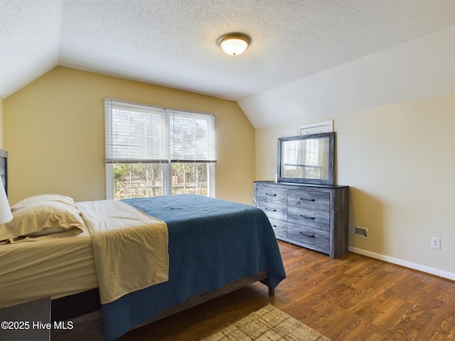 bedroom featuring vaulted ceiling, dark wood-type flooring, and a textured ceiling