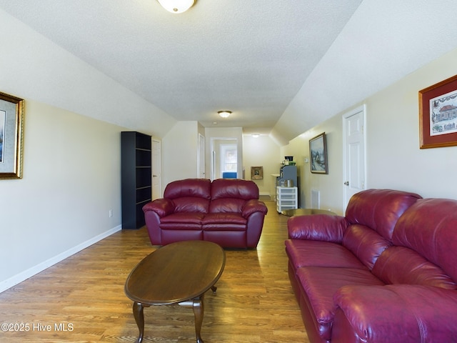 living room with wood-type flooring, a textured ceiling, and lofted ceiling