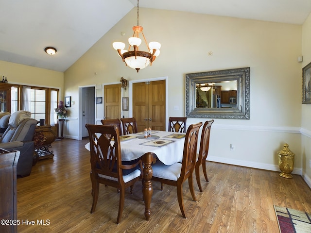 dining room with high vaulted ceiling, a notable chandelier, and hardwood / wood-style flooring