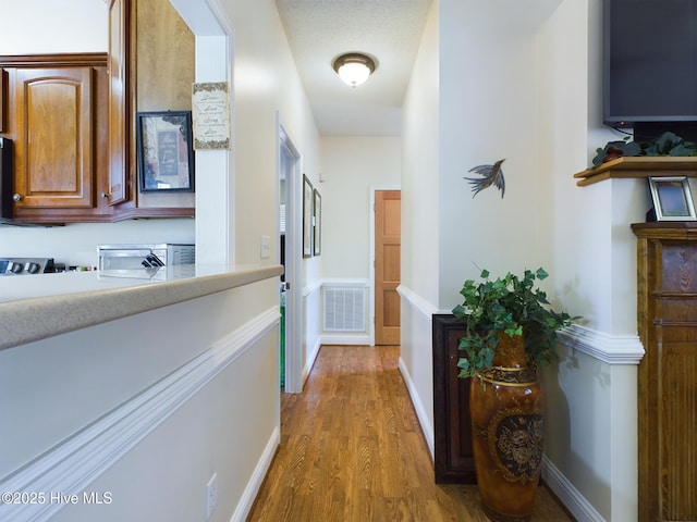 hall with a textured ceiling and hardwood / wood-style flooring