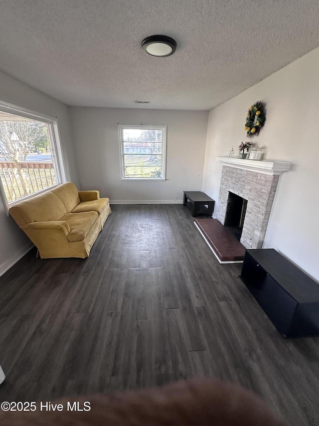 living area featuring baseboards, a textured ceiling, a fireplace, and dark wood-style flooring