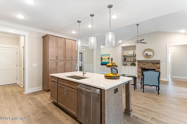 kitchen featuring built in shelves, sink, a center island with sink, dishwasher, and pendant lighting