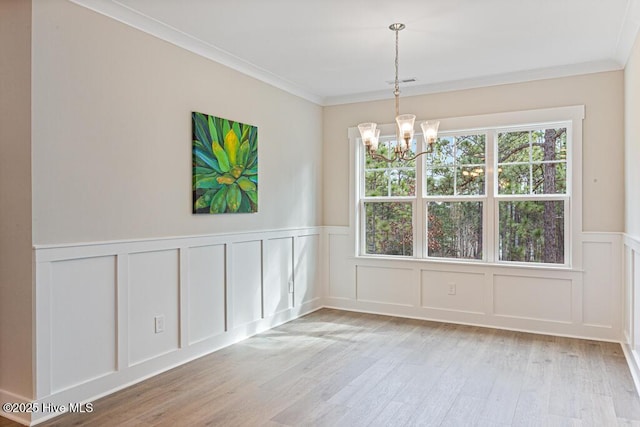 unfurnished dining area featuring ornamental molding, a chandelier, and light wood-type flooring