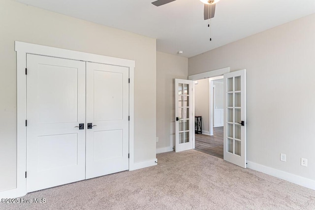 unfurnished bedroom with light carpet, a closet, french doors, and ceiling fan