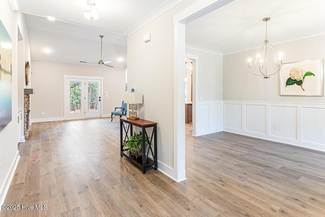 interior space with crown molding, wood-type flooring, an inviting chandelier, and french doors