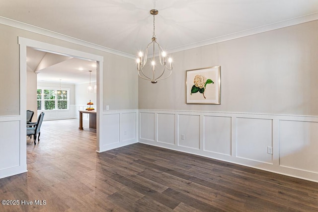 unfurnished dining area with dark wood-type flooring, crown molding, and a notable chandelier