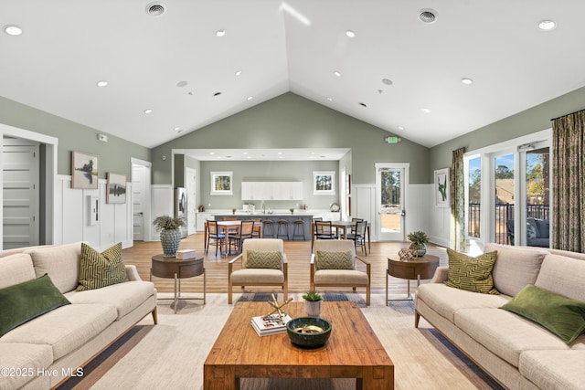 living room featuring high vaulted ceiling and light wood-type flooring