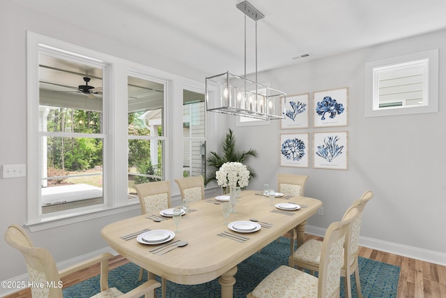 dining space with hardwood / wood-style floors and ceiling fan with notable chandelier