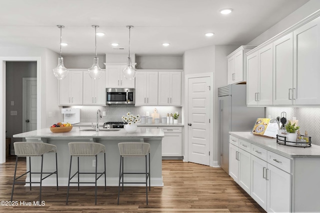 kitchen with appliances with stainless steel finishes, a kitchen island with sink, and white cabinets