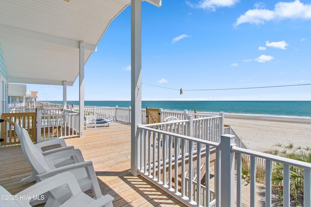 wooden terrace featuring a water view and a beach view