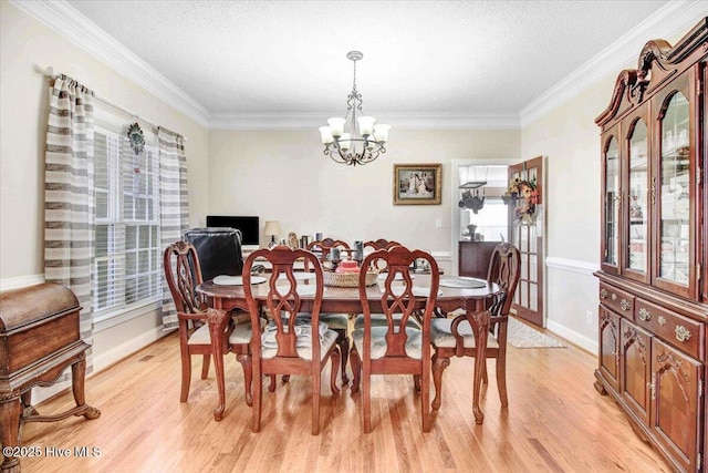 dining area featuring light hardwood / wood-style floors, a textured ceiling, crown molding, and an inviting chandelier