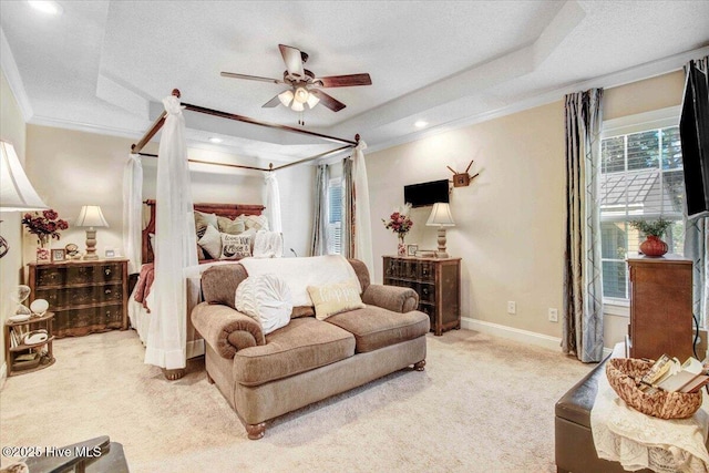 carpeted bedroom featuring a raised ceiling, ceiling fan, and ornamental molding